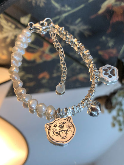 Close-up of the the Paw Print Charm and the Heart Pendant on our Dog Pearl Pet Face Bracelet